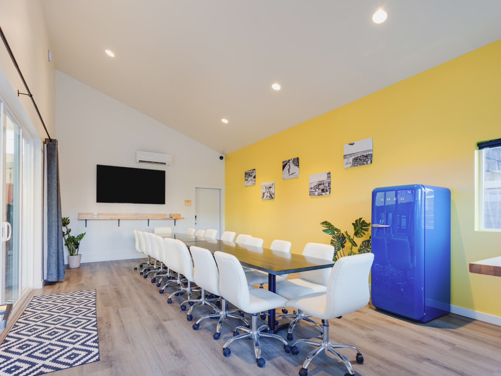 Conference room with a long shared table and mounted TV